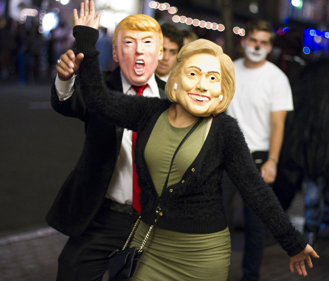 A person wearing a Trump mask chases another person wearing a Clinton mask