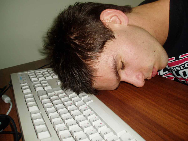 A man sleeps at a computer keyboard