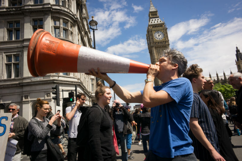 A man shouts into a traffic cone as part of a protest against Brexit