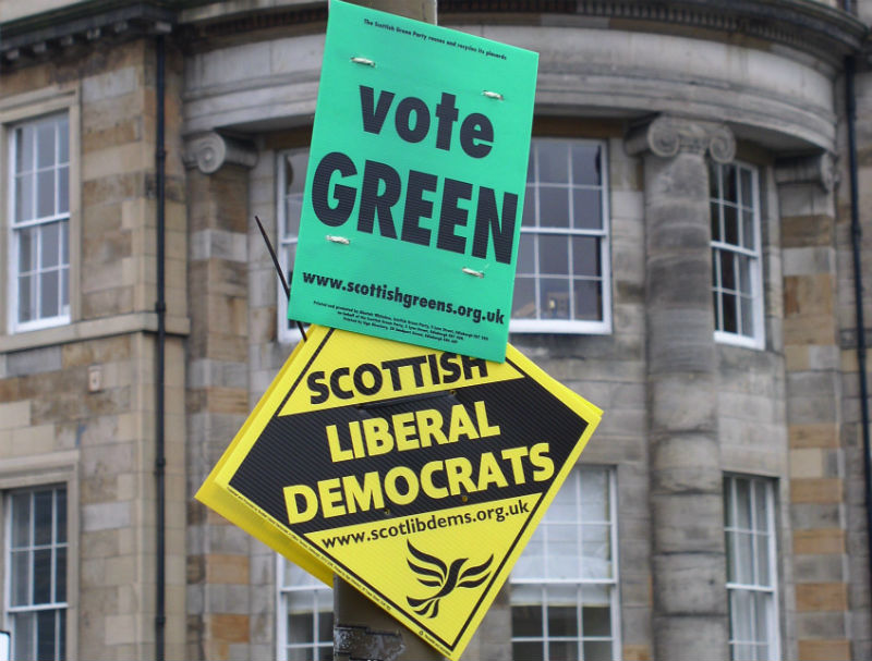 Green and Lib Dem campaign material shares a lamppost