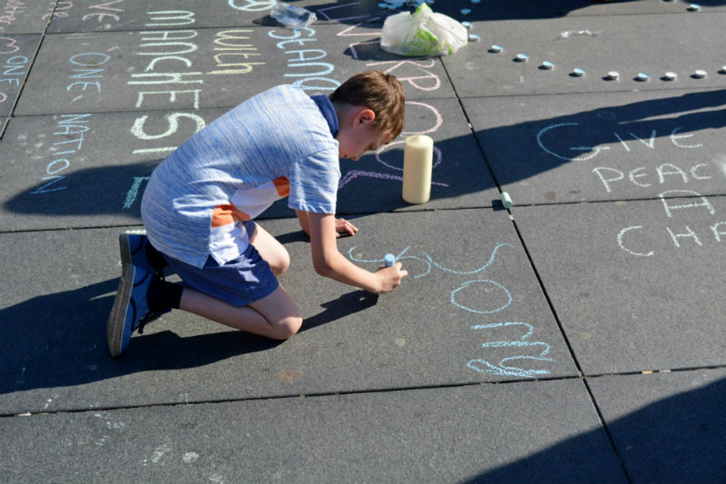 At a vigil in Liverpool following the Manchester attacks, a boy writes a message of support