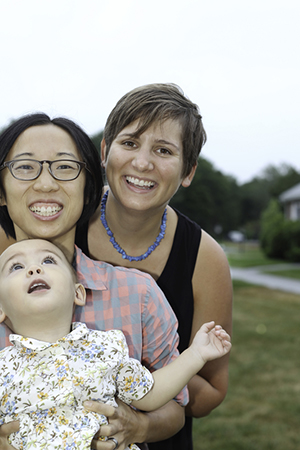 Two women hug with their smiling baby