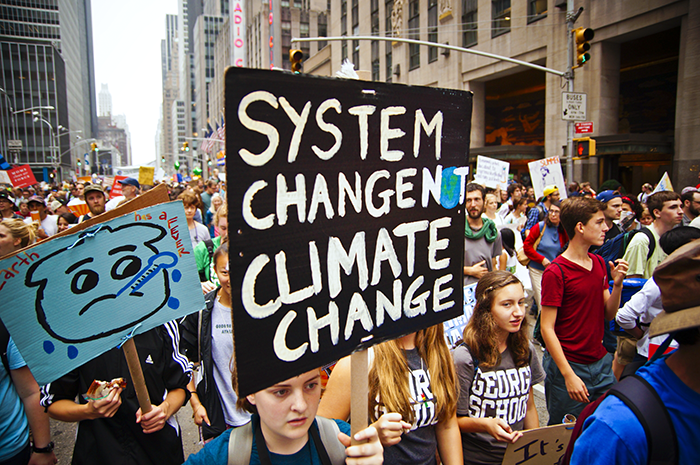 People protesting with signs that read 'system change not climate change'.