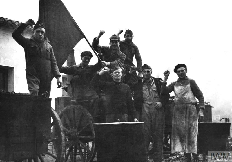 Members of the International Brigade in the British cookhouse at Albacete raise their fists in the Communist salute