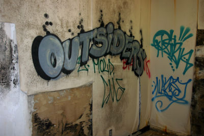 The word 'Outsiders' spray-painted on a wall