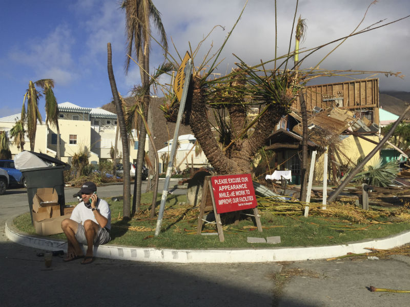 A man sits next to sign in the marina of Nanny Cay on the British Virgin Island of Tortola, which suffered widespread damage and destruction when Hurricane Irma passed over on 6 September 2017
