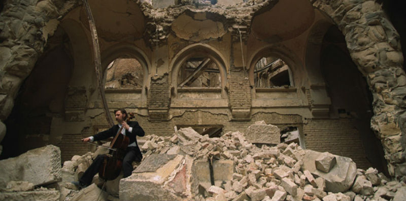 The image was taken during the war in 1992 in Sarajevo in the partially destroyed National Library. The cello player is local musician Vedran Smailović. 