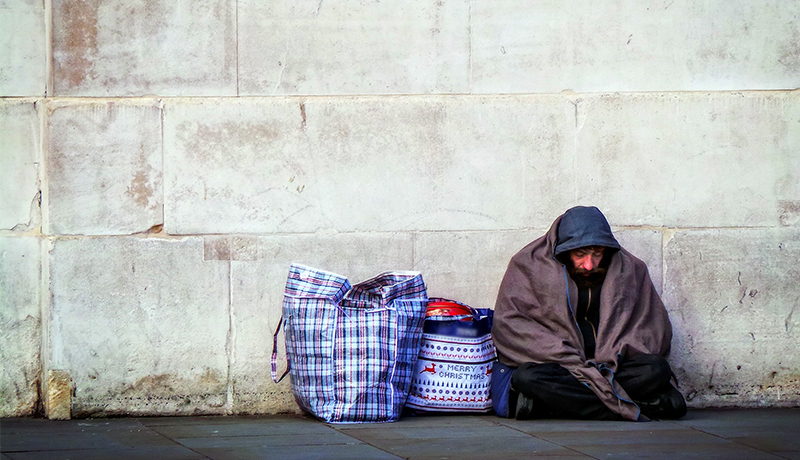 A homeless person against a wall