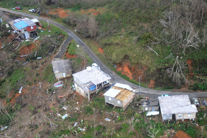 Residents wave from the roof of a house, bottom right, in Jayuya, Puerto Rico, Oct. 14, 2017
