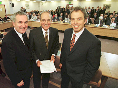 British Prime Minister Tony Blair (R), US Senator George Mitchell (C) and Irish Prime Minister Bertie Ahern (L) smiling on April 10, 1998, after they signed an historic agreement for peace in Northern Ireland, ending a 30-year conflict. 