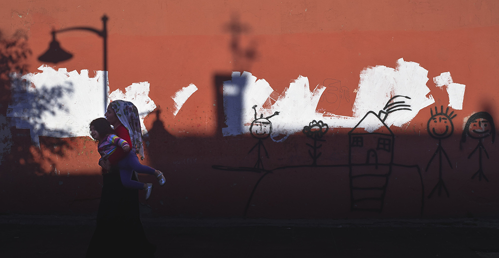 A Syrian mother carrying her daughter back to a safe place in Istanbul, Turkey