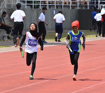 2 girls running on an athletics track with hijabs