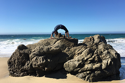 woman doing yoga on a rock on the beach