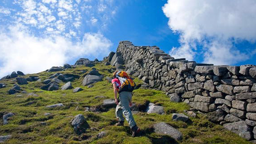 Mourne Mountains, Co Down, Ireland; Hiker Beside The Mourne Wall On The Slopes Of Slieve Bearnagh
