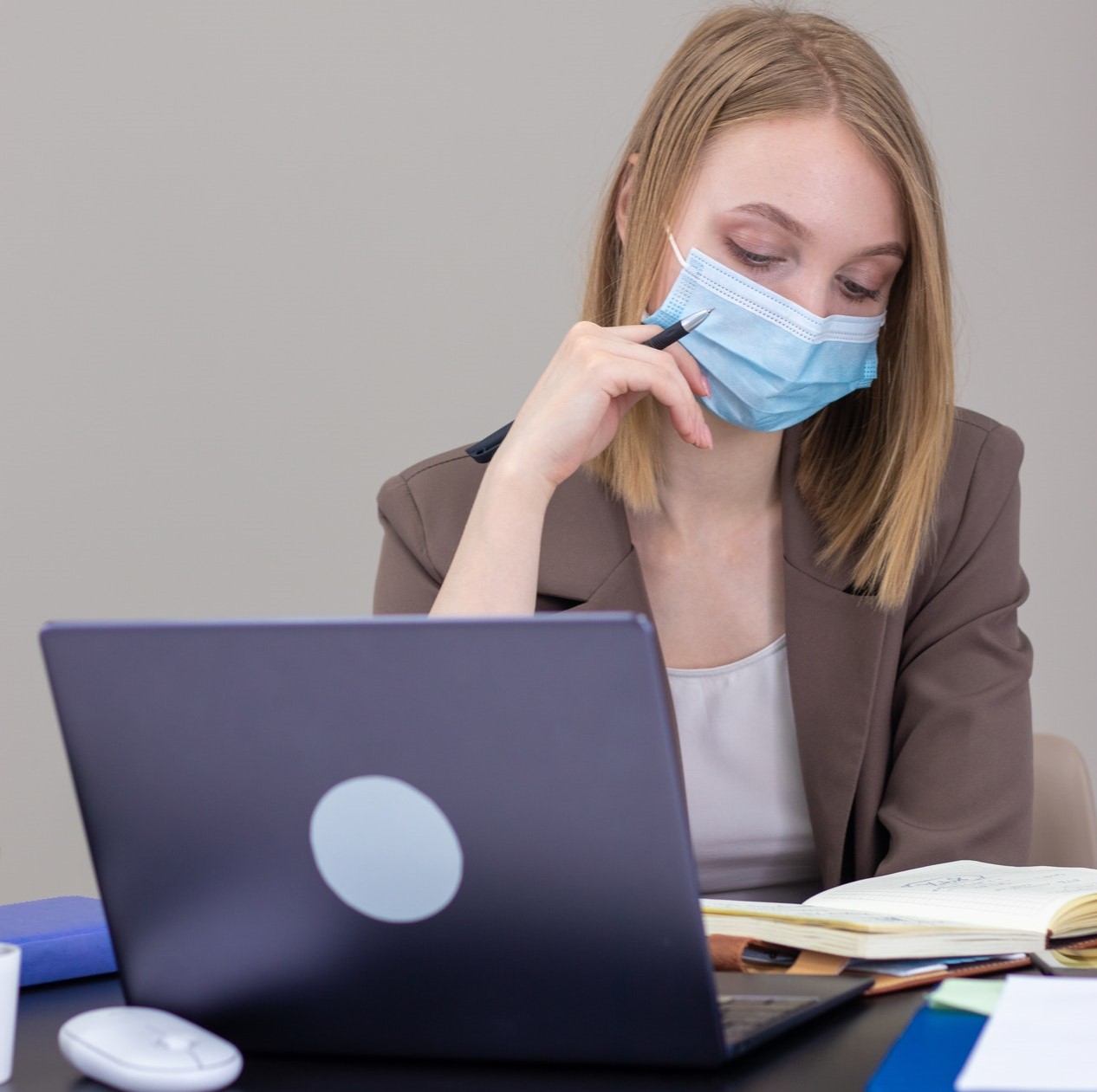 Woman working at laptop in a mask