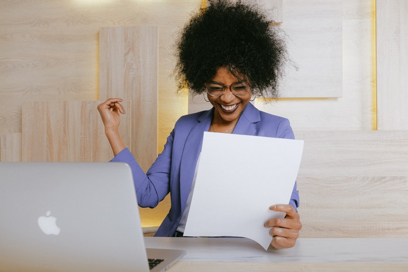 woman at work smiling while holding a paper