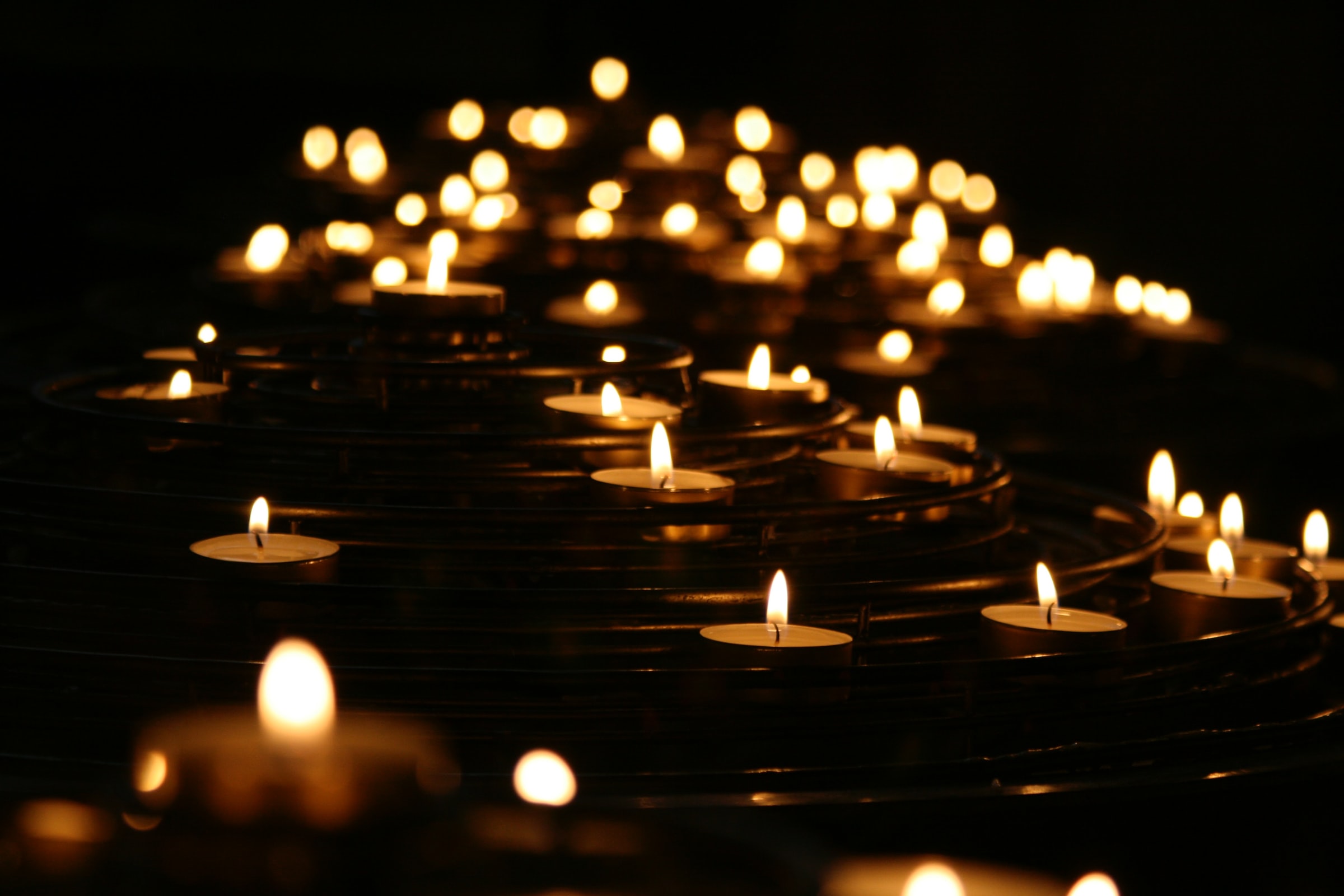 Several lit candles against a dark, black background.