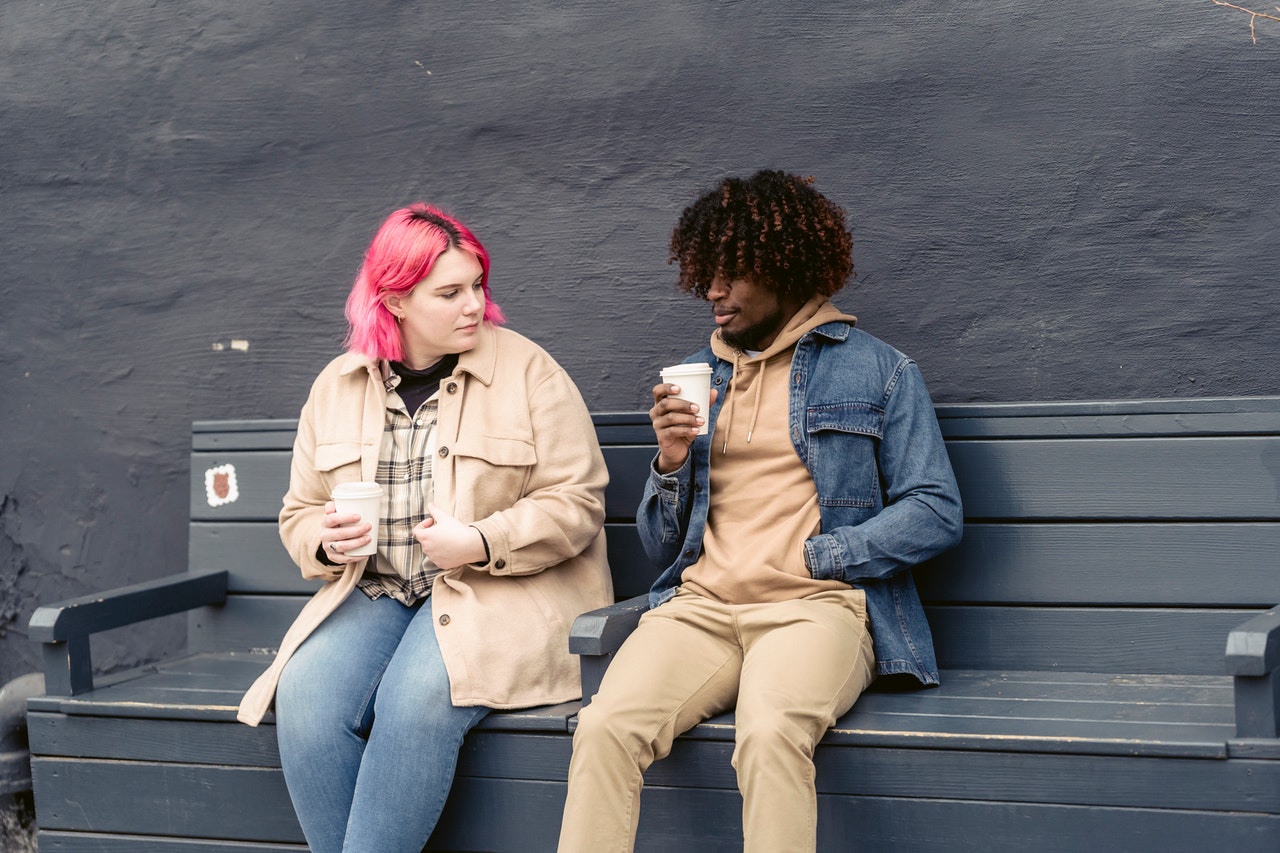 friends sitting on a bench drinking coffee
