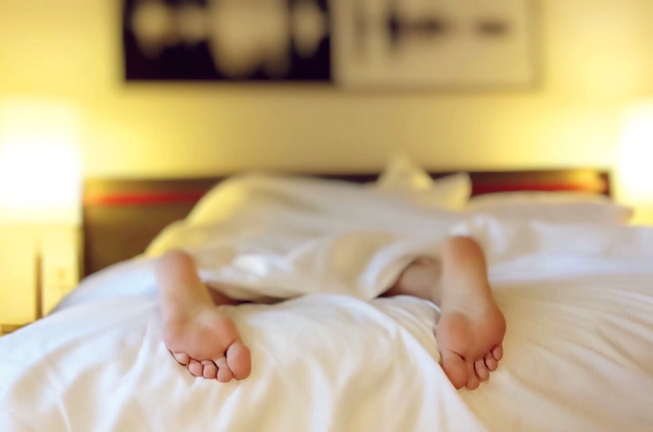 person asleep in bed with their feet poking out of the duvet