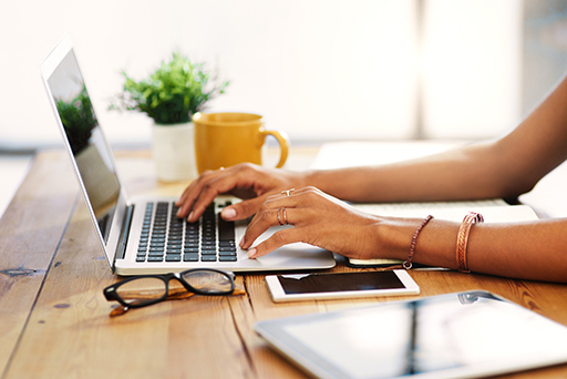 A photo of a person’s hands typing on a laptop.