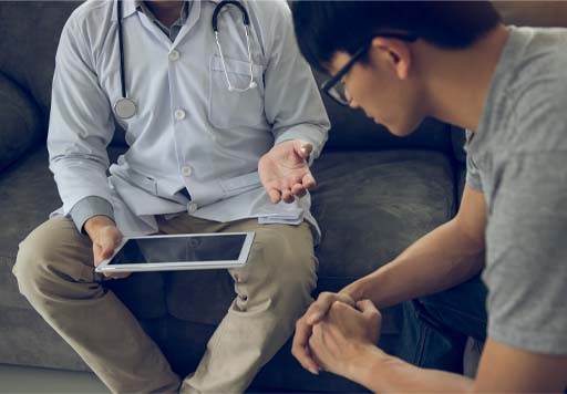 A photograph of two people talking, one person is holding a computer tablet.