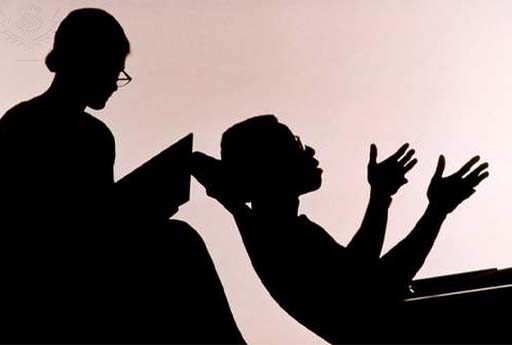 A person lying on a couch in a counselling session. Photographed in silhouette.