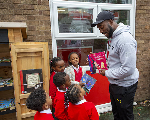 An adult showing a book to a group of young children outside.