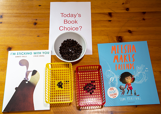 Two books next to a piece of paper which says ‘Today’s Book choice?’and a bowl of beans.