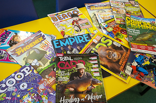 A table with magazines, such as Beano, The Phoenix and Empire laid out on it.