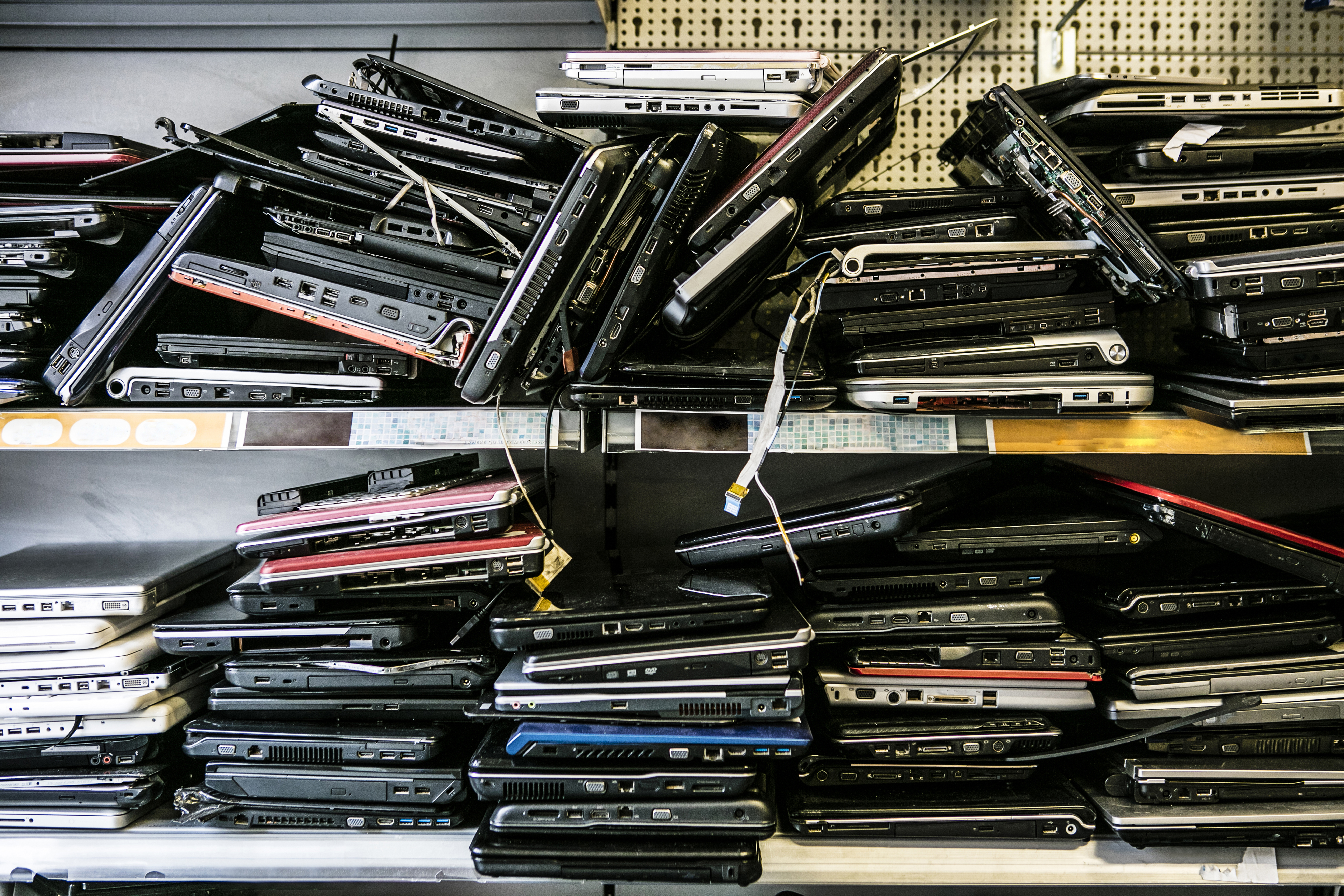 A pile of old discard laptop devices on a shop shelf