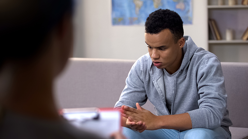 A teenage boy sat down looking anguished.