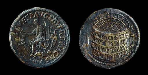This image shows both sides of a small copper coin. On the left, one side of the coin is depicted, showing a male figure wearing a toga, seated and facing his left. He is surrounded by a variety of objects which appear to be shields and other weapons. Letters around the edge of the coin spell out an inscription in Latin. On the right of the image, the other side of the coin is depicted. It appears to show a large circular building, as if viewed from a slightly elevated position. On the outside of the building, there appear to be four storeys, each consisting of a row of archways. The inside of the building can be seen, also represented by several different levels, and containing many small dots which may represent people.