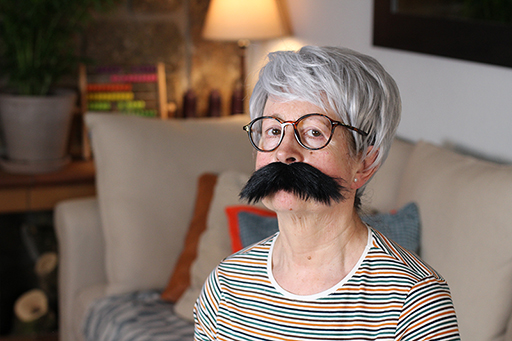 A photograph of a person wearing a wig, glasses and a false moustache.