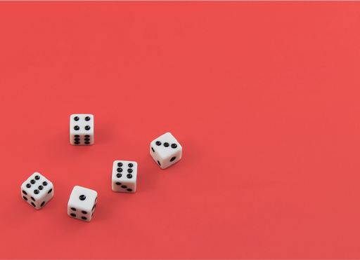 This is a decorative photograph showing a collection of dice against a red background.