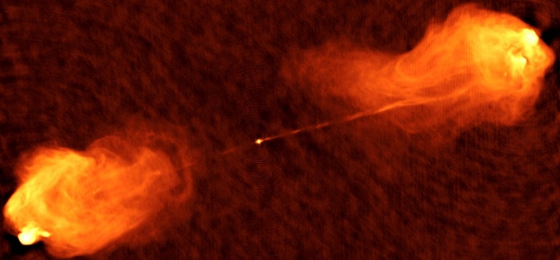 This is an image taken at radio wavelengths, showing jets of charged particles being ejected from the nucleus of the galaxy Cygnus A. Flame-like emissions can be seen against a dark red background.