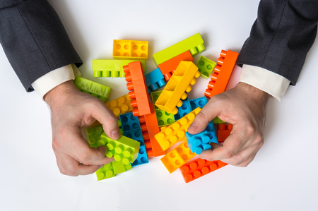 A pair of hands playing with a pile of coloured blocks.