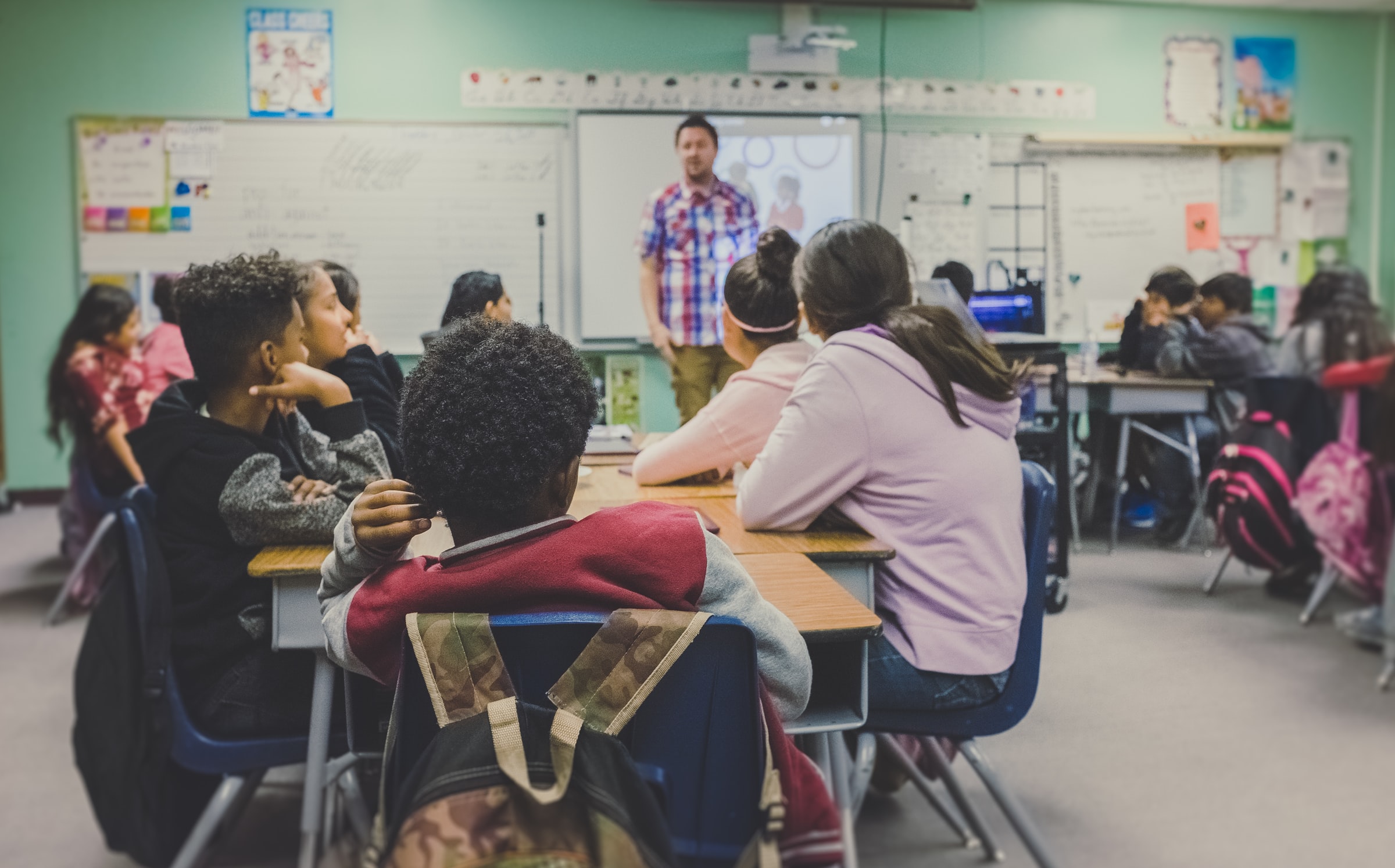 Teacher standing in front of children in a classroom.