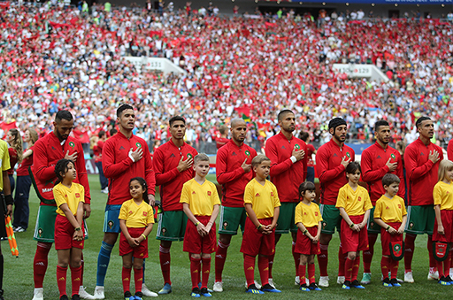 A photograph of the Morocco men’s team singing the national anthem on the pitch.