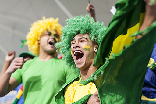 A photograph of football fans wearing bright colours and celebrating.