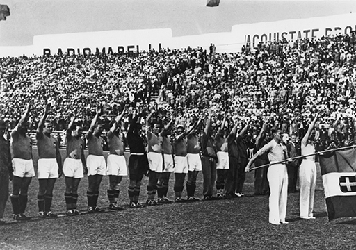 A black-and-white photograph of the Italian players holding an arm in the air.
