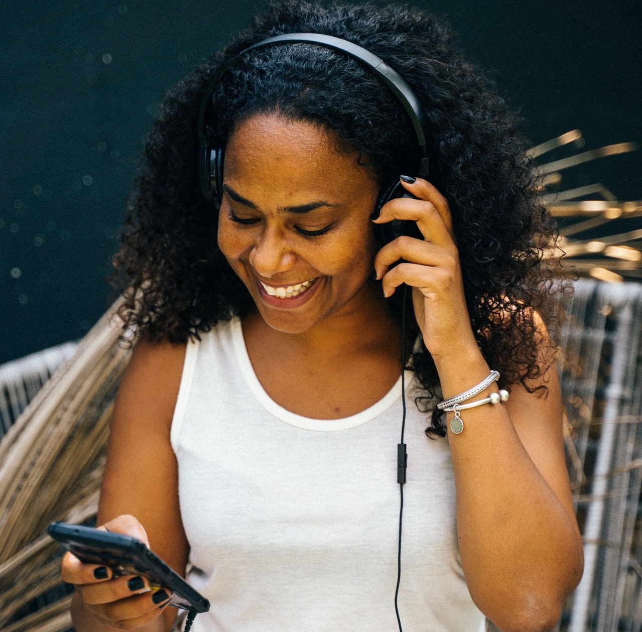 Woman wearing headphones and listening to a podcast on her mobile phone 