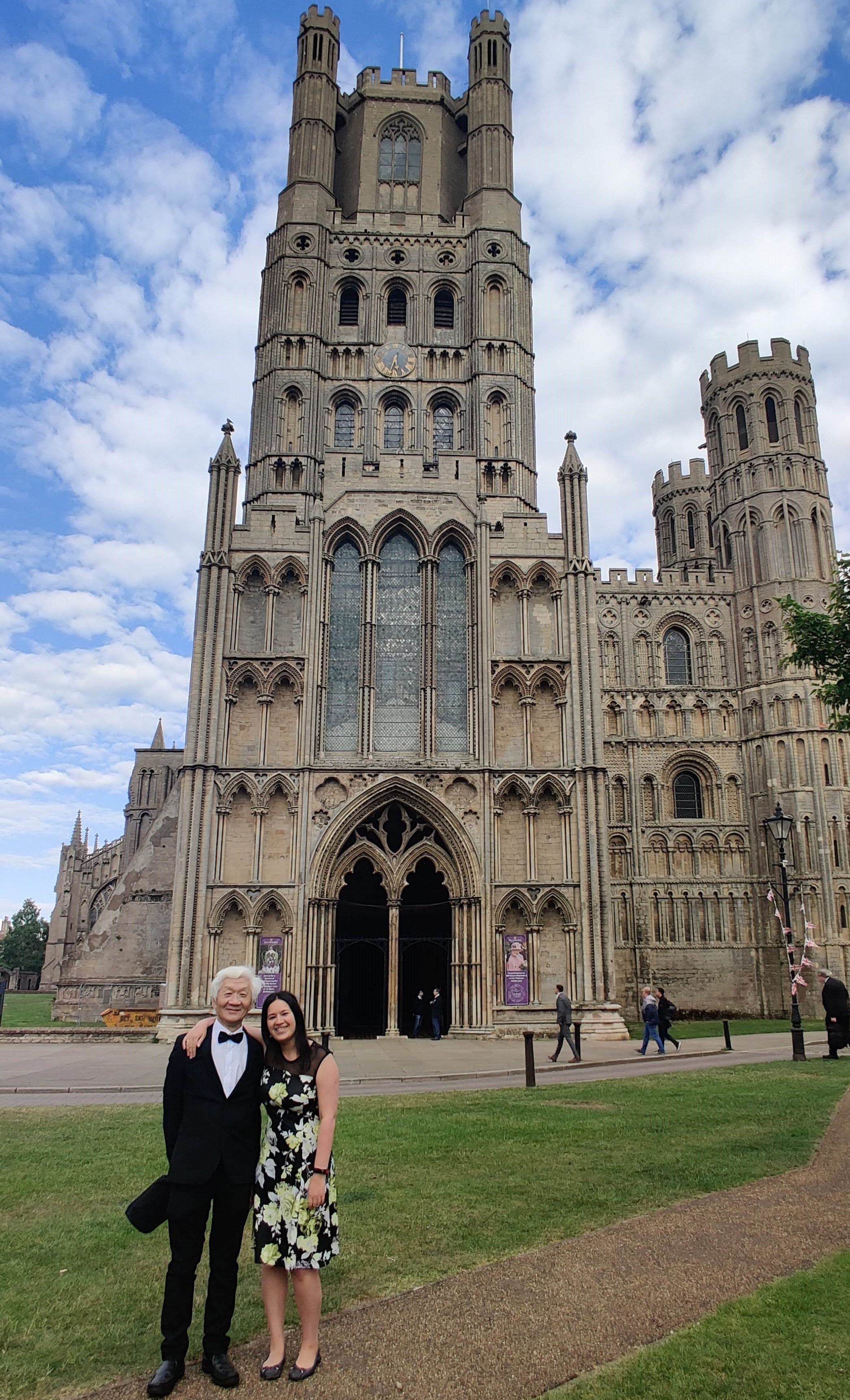 Dr Laura Tan standing outside Ely Cathedral with her father following graduation ceremony