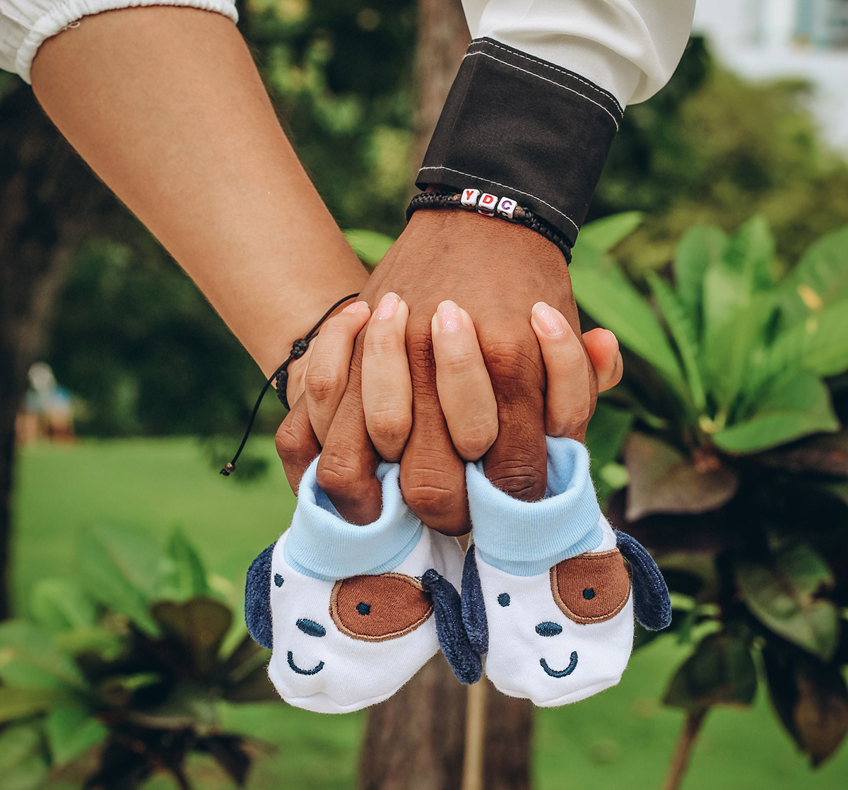 A couple hold a pair of baby shoes together.