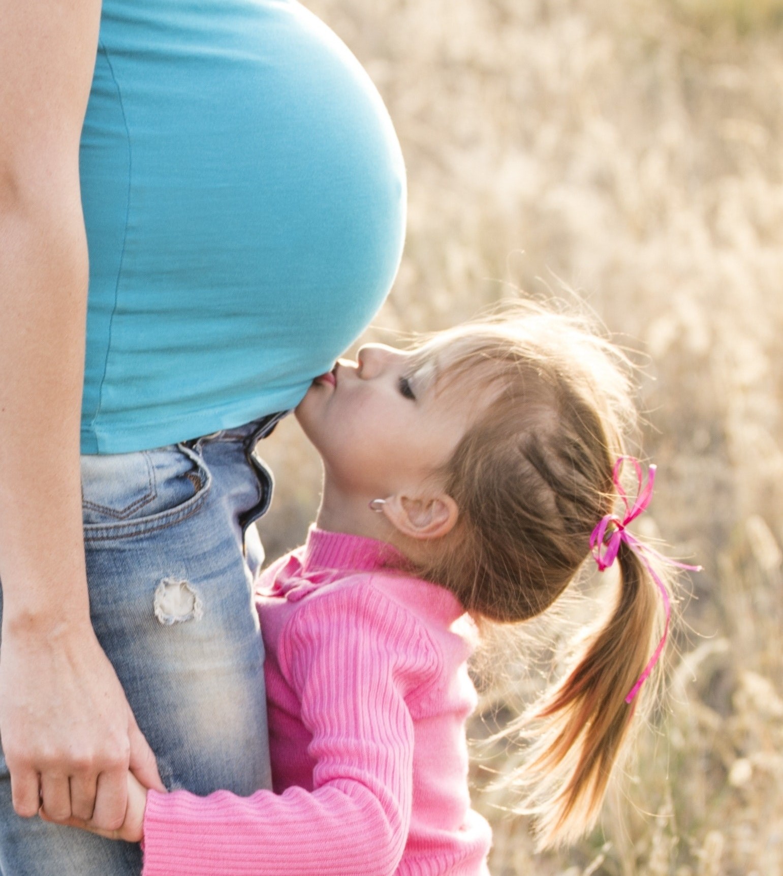 Young child kissing pregnancy 'bump'