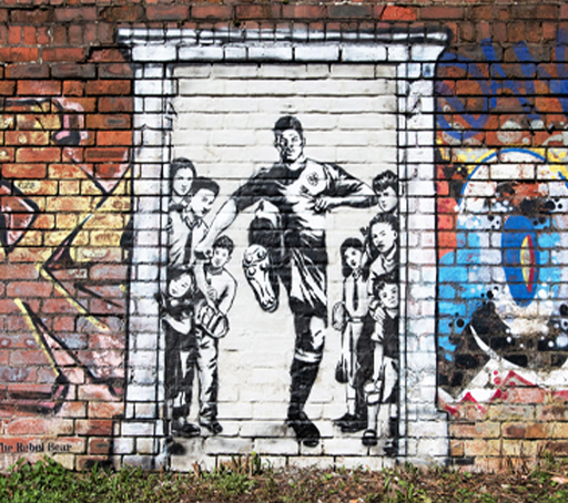 A photograph of a Mural of Marcus Rashford kicking down a door.