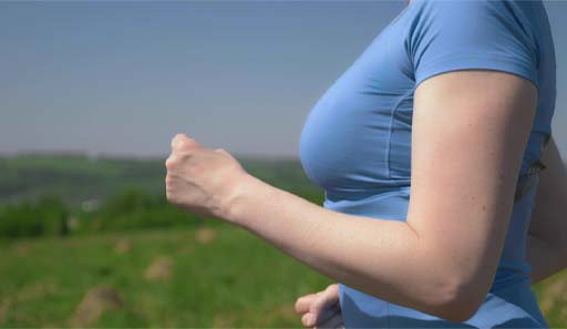 The image shows a side on view of a female from her chest down to her waist. She is wearing a t-shirt but the image indicates that she has she is wearing an appropriate sports bra