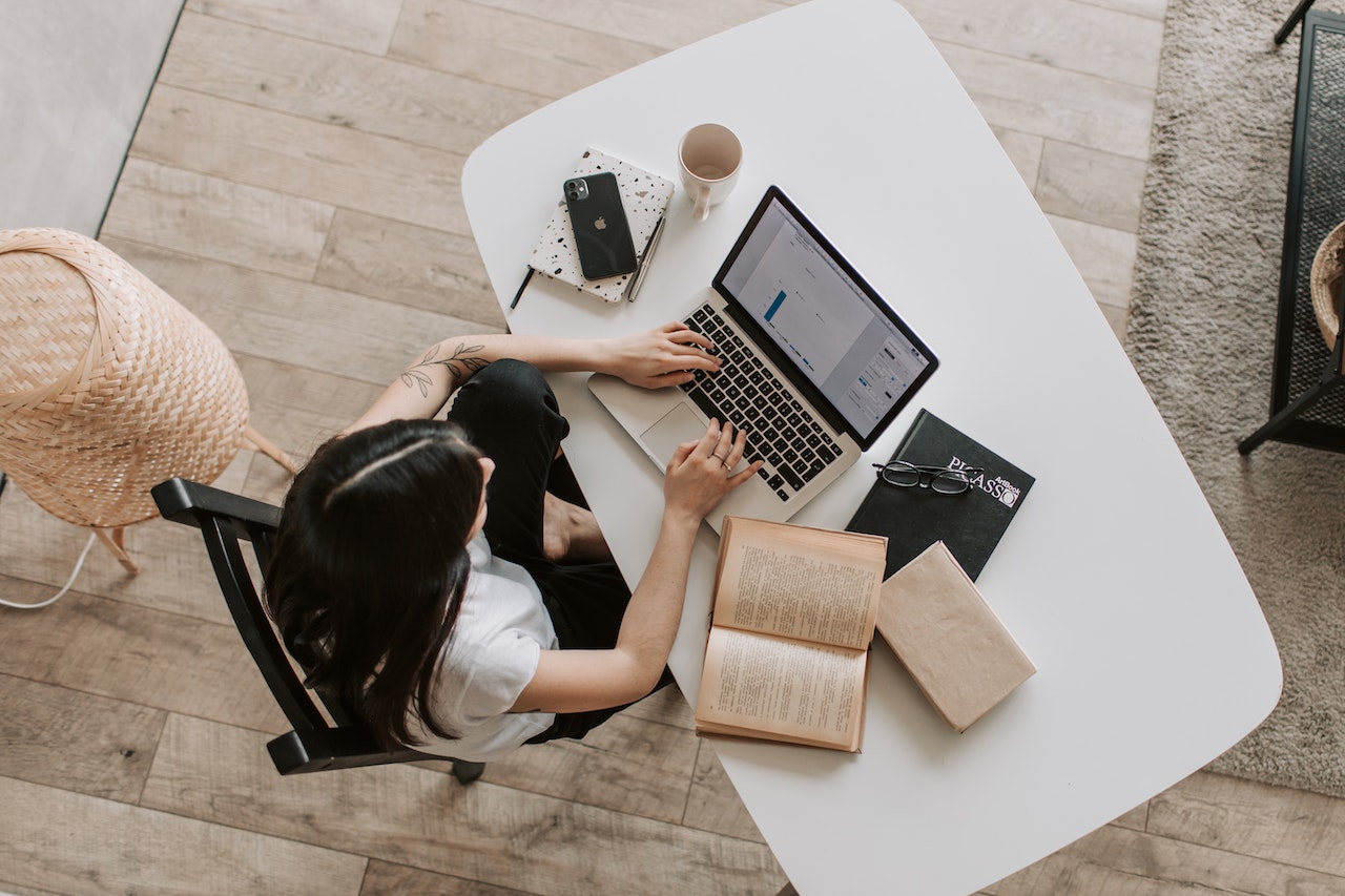 Student at her desk with a laptop, phone and notebook
