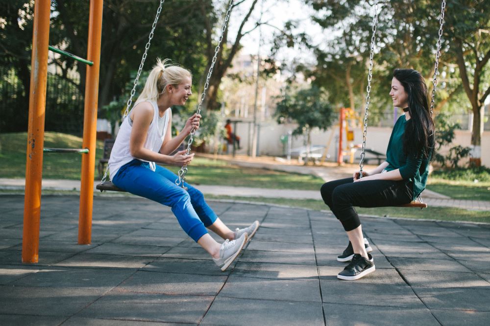 two women on a swing, facing one another