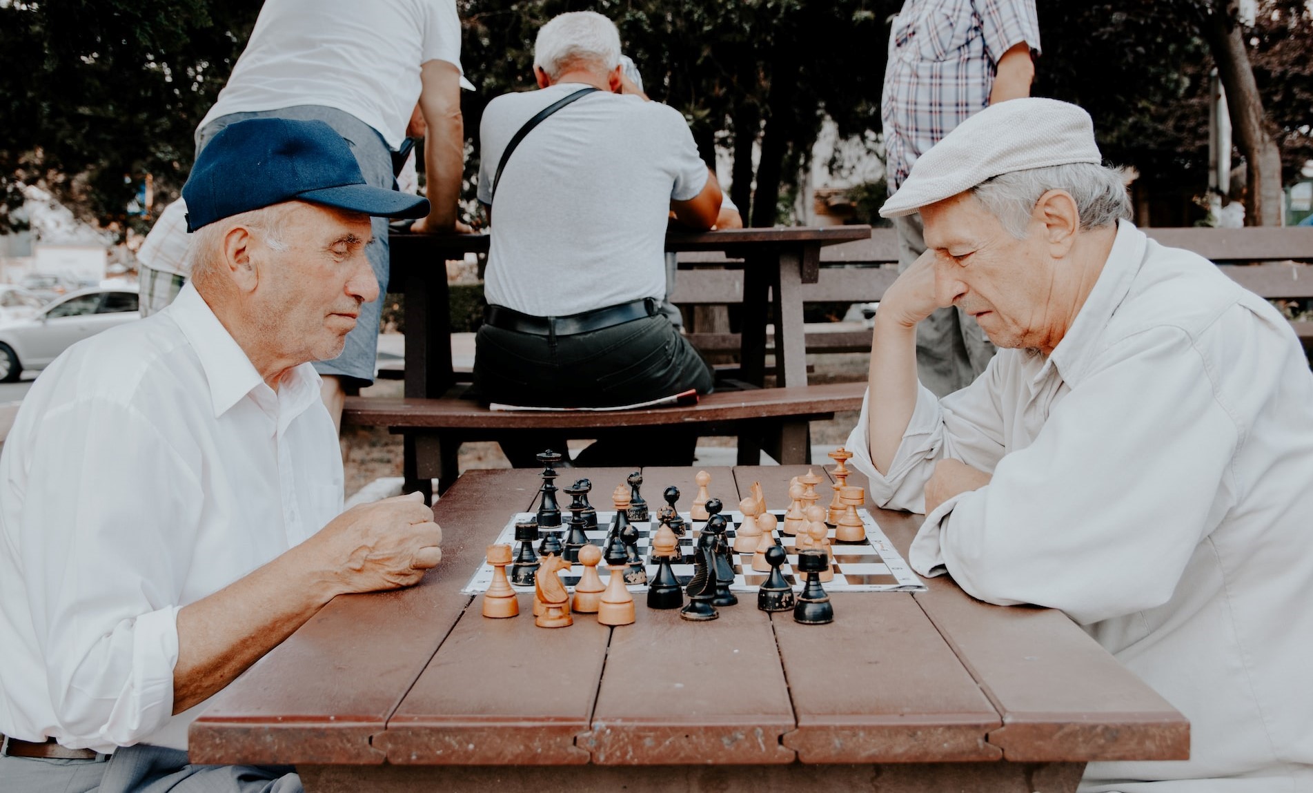 Two seniors (men) playing chess outdoors.
