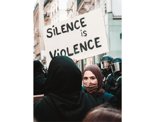 A photograph of protesters holding up a sign: Silence is violence.
